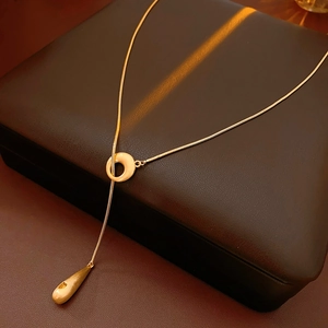 Detailed macro shot of gold plated teardrop pendant and link chain on leather case