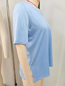 Dettaglio t-shirt azzurra con scollo a V, spacco laterale e trama del tessuto traspirante