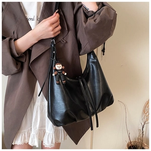 Detail view of large black soft leather hobo bag with drawstring and monkey pendant