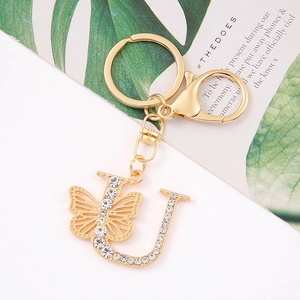 Detail of gold letter U keychain with sparkling crystals and a butterfly charm decoration
