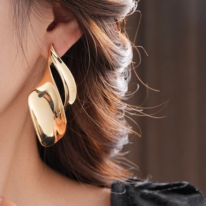 Macro shot of irregular twisted gold leaf earring worn by a model in luxury style