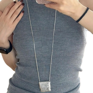 Silver snake chain necklace with square woven metal pendant on female model