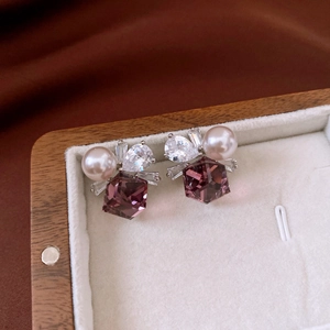 Macro detail of jewelry earrings with pink pearl, white zircon and purple crystal