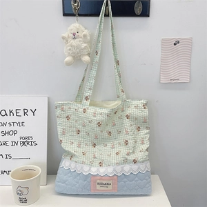 Detail of canvas tote featuring mint grid print, lace trim, and blue quilted texture
