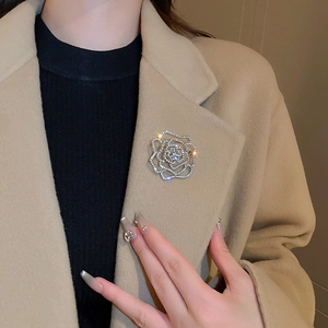 Close-up of diamond-encrusted hollow rose brooch on a khaki coat lapel for elegant look