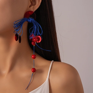 Ethnic style long tassel earrings with blue cord and red resin beads shown on model