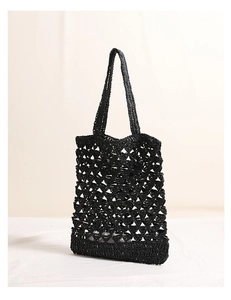 Close-up detail of black hollow woven straw bag with geometric diamond mesh texture