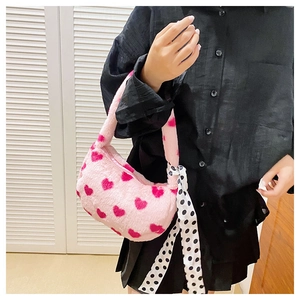 Detailed texture of pink plush handbag with red heart pattern and polka dot scarf detail
