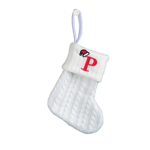 Detail of white cable knit Christmas stocking with red embroidered letter P and mini hat