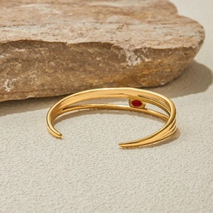 Dettaglio del bracciale aperto in oro 18K acciaio con pietra rossa e design a strati