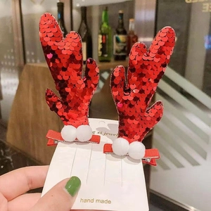 Detail of handmade Christmas reindeer hair clips with red sequins and soft white pompoms
