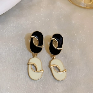 Close-up of vintage black and white oval earrings with gold metal trim on fabric