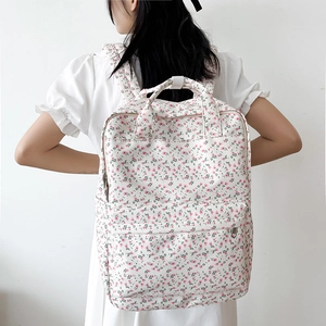 Detailed close-up of floral backpack fabric texture and white straps on a model