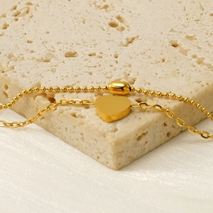 Golden heart pendant and bead chain set on stone background for women