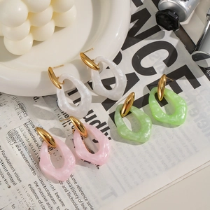 Minimalist geometric acrylic earrings in white, pink, and green on a ceramic plate