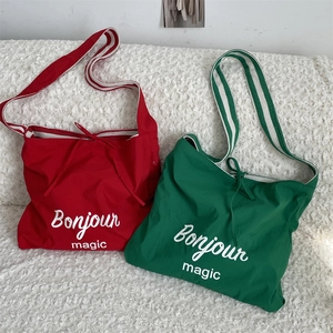 Détail des sacs cabas rayés rouges et verts avec imprimé Bonjour Magic sur fond en peluche