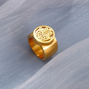 Detailed shot of gold Hamsa ring with openwork design on textured blue fabric