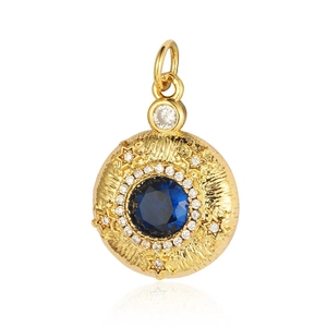Dettaglio macro del ciondolo tondo dorato con gemma blu e accenti di stelle in zircone