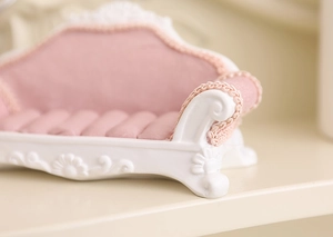 Detail of pink miniature sofa jewelry holder with lace trim and embossed floral patterns