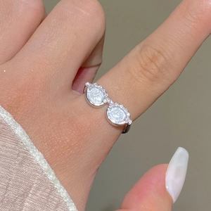 Close-up of creative silver sunglasses ring with pavé stones worn on an index finger