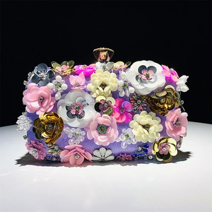 Detail shot of purple evening clutch featuring 3D floral beadwork and metallic ball clasp