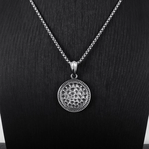 Detailed close-up of a silver hammered texture circular pendant on a box chain