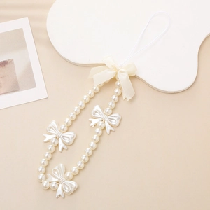 Sweet white pearl phone strap with a butterfly bow charm on a clean beige background
