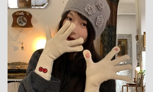Detail of beige knit gloves with red bow embroidery and fingerless touch screen tips