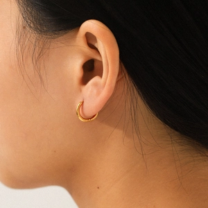 Close-up of model wearing small minimalist 18K gold plated stainless steel hoop earrings