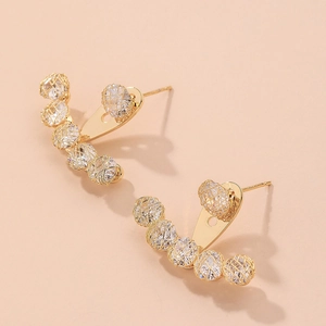Detailed macro view of gold-plated mesh earrings with clear sparkling zircon stones