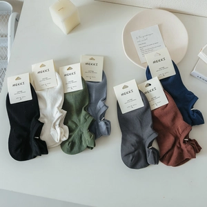 Flat lay of multi-colored low cut cotton socks with ribbed texture on beige surface