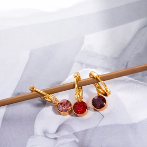 Pendientes de piedra de nacimiento con circonitas en rosa y rojo sobre madera