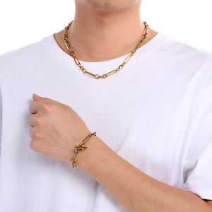 Gros plan sur un ensemble collier et bracelet trombone doré avec fermoir OT sur un mannequin