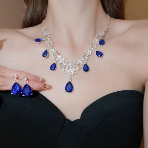 Detailed view of silver necklace and teardrop blue crystal earrings on model