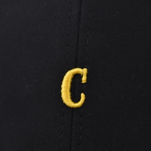Detailed macro view of yellow 3D embroidered letter C on black cotton baseball cap