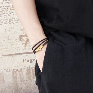 Détail d'un bracelet multicouche en cuir noir avec fermoir aigle doré sur le poignet
