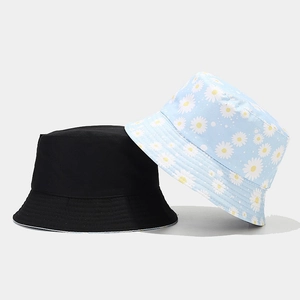 Detail of reversible bucket hat showing solid black side and blue floral daisy pattern