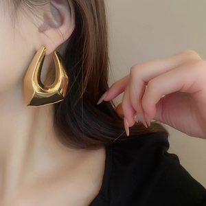 Gros plan de boucles d'oreilles géométriques en U dorées avec un éclat métallique