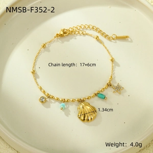 Detail of gold ocean-themed bracelet with shell and starfish charms on ceramic tray