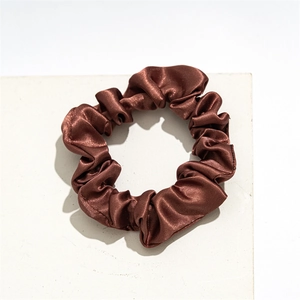 Detail view of smooth dark brown satin fabric scrunchie with soft pleated texture