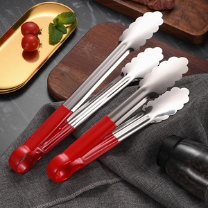Stainless steel food tongs with red handles and wavy tips on a dark wooden background