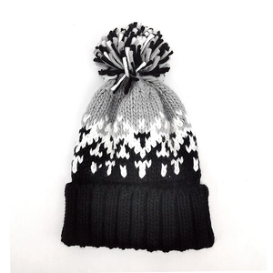 Close-up of winter knit beanie showing tricolor pom-pom and gradient jacquard texture