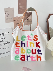 Detail of Let's think about earth embroidered letters on white canvas tote bag