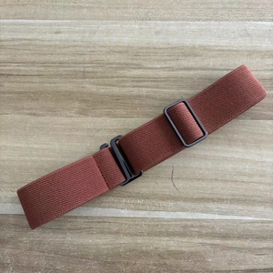 Brown elastic invisible stretch belt for women with black flat buckle on a wooden surface