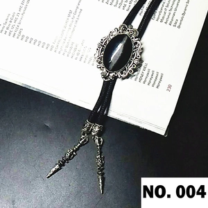Detail of silver crown bolo tie with black oval stone and metal tips on a book background