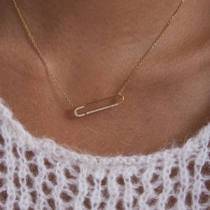 Close-up of 18K gold-plated stainless steel safety pin necklace with pavé crystal accents