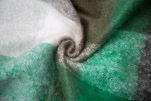 Close-up of knit fabric texture showing green, brown, and white checkered pattern details