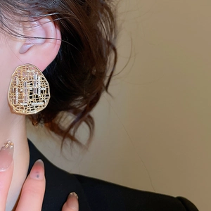 Détail d'une boucle d'oreille ovale ajourée plaquée or avec zircons sur un modèle