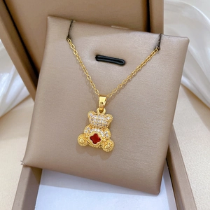 Detail of gold titanium steel bear necklace with red clover and sparkling crystals