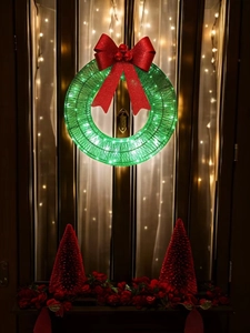 Close-up of green wire Christmas wreath with glowing LED lights and a red glitter bow